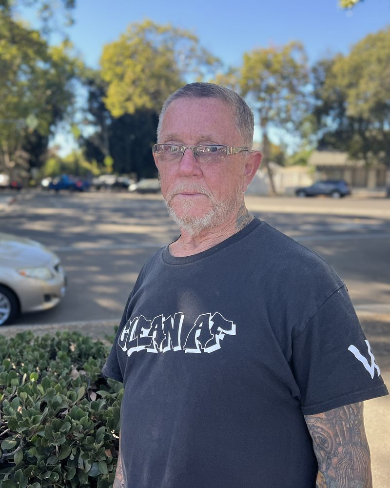 Donald D. stands outdoors in a parking lot on a sunny day.
