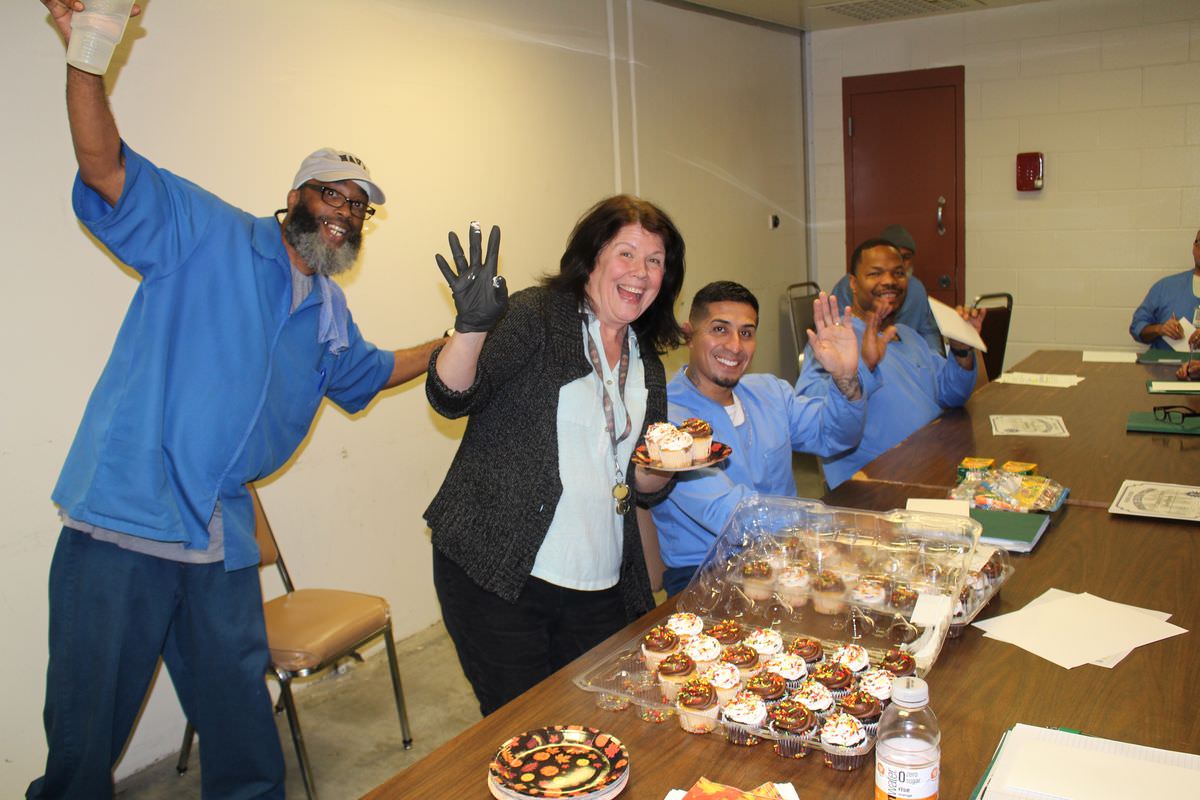 Incarcerated men celebrate with a Friends Outside staff member at a class party with cupcakes.