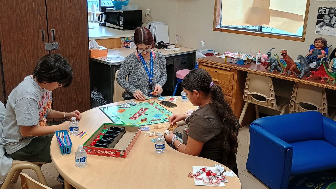 Children do crafts at a table in a Visitor Center while staff help.