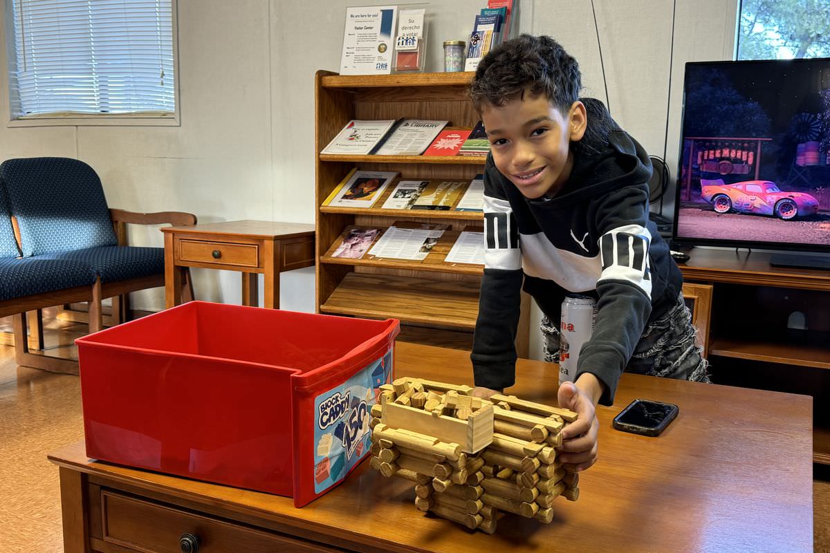 A boy plays with a wooden toy in a Visitor Center playroom.