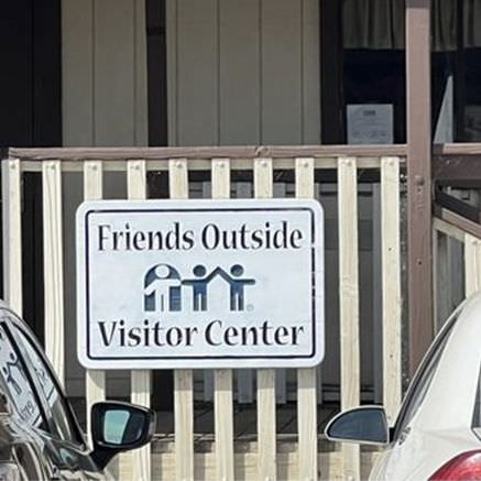 A Friends Outside Visitor Center sign on a fence outside the center.